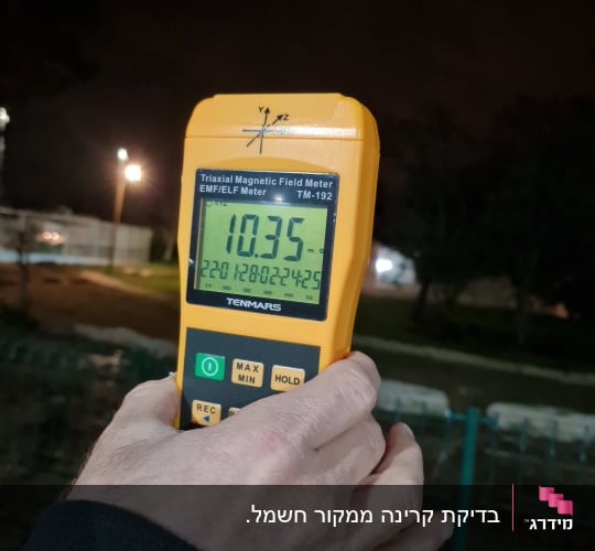 מד קרינה מגנטית מוחזק ביד בלילה